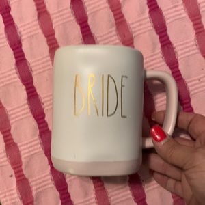 Rae Dunn mug. White mug, pink around bottom with Bride wrote in gold.